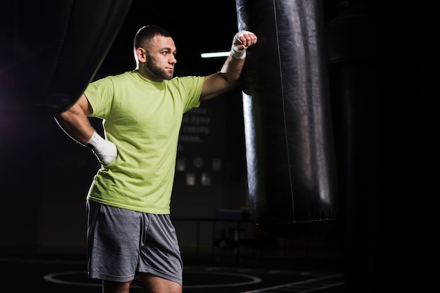 Side view of male boxer in t-shirt with punching bag