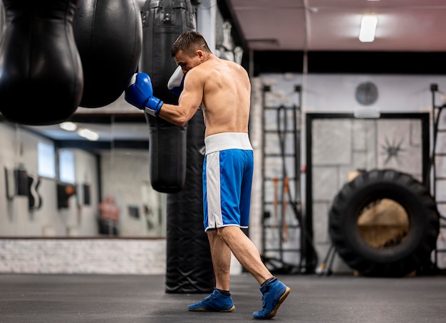 Вид сбоку тренировки боксера мужского пола с защитными перчатками