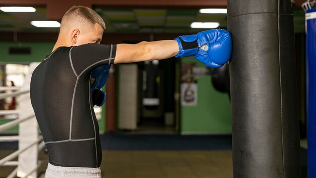 Side view of male boxer with gloves training