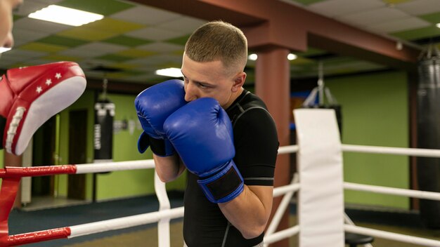 Вид сбоку на боксера-мужчину с тренером и перчатками
