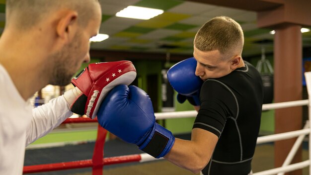 Вид сбоку боксера-мужчины с тренером рядом с рингом