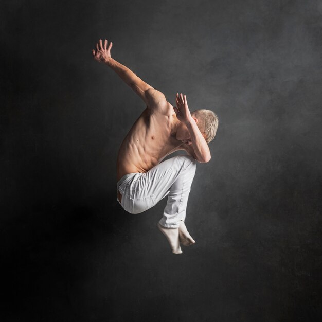 Side view of male dancer posing in mid-air