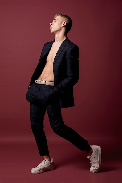 Side view of male dancer posing in suit without shirt and sneakers