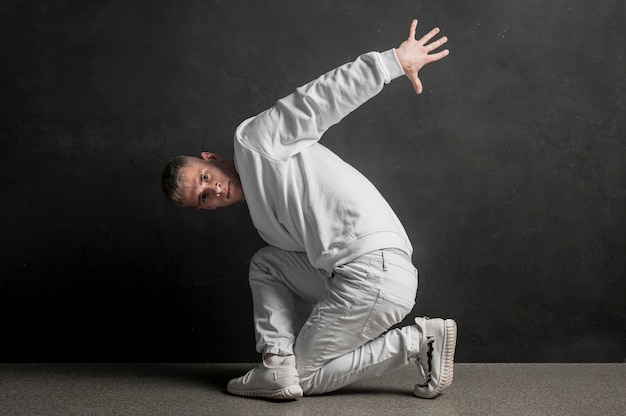 Vista laterale del ballerino maschio che posa con il fumo