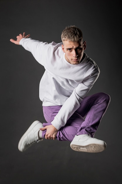 Side view of male dancer in purple jeans posing in mid-air