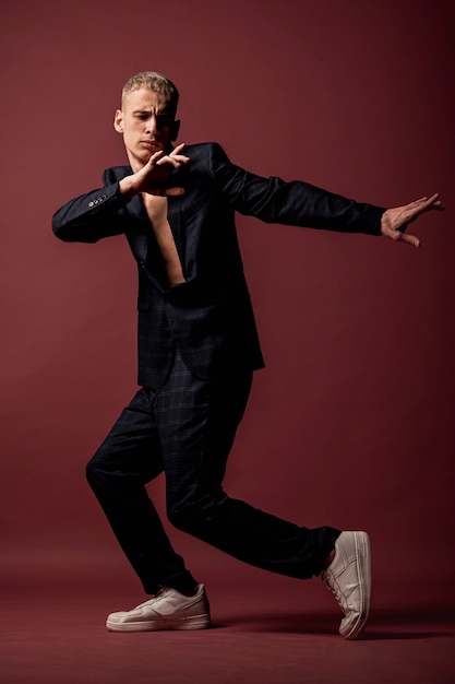 Side view of male dancer in suit and sneakers striking a pose