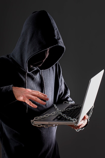 Вид сбоку мужской хакер с ноутбуком защищен металлической цепью