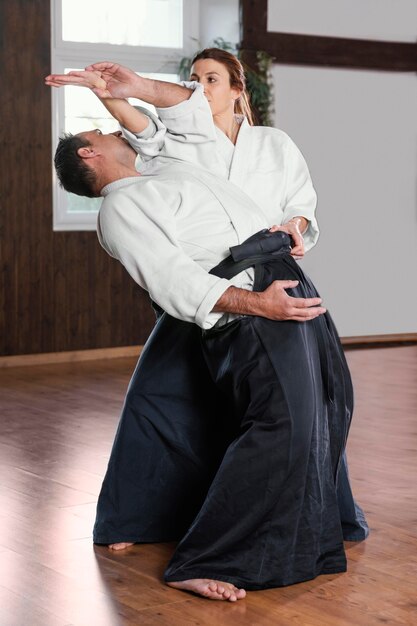 女性の訓練生と練習ホールで訓練している男性の武道のインストラクターの側面図