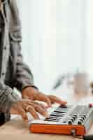 Free photo side view of male musician at home playing electric keyboard