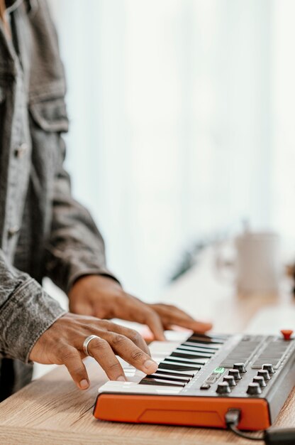 Side view of male musician at home playing electric keyboard