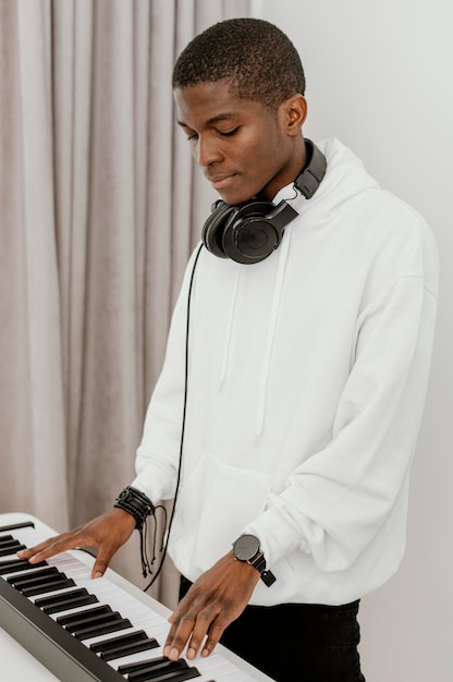 Free photo side view of male musician at home playing electric keyboard