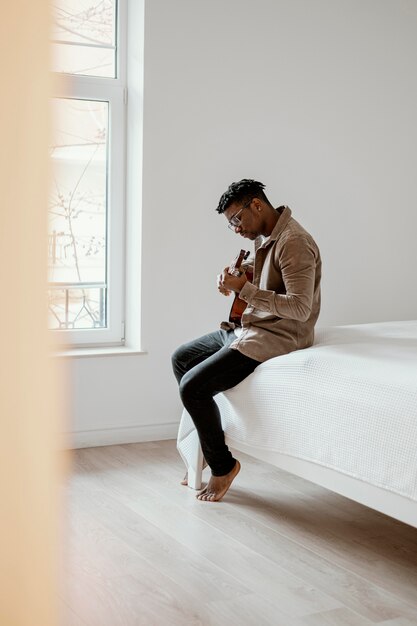ベッドでギターを弾く男性ミュージシャンの側面図