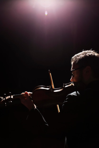 Free photo side view of male musician playing the violin with copy space