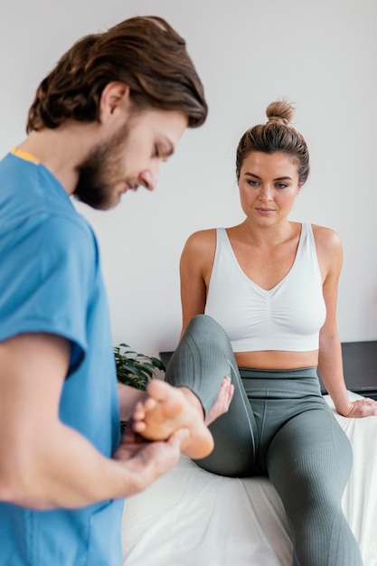 side view of male osteopathic therapist checking female patient's leg movement