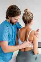 Free photo side view of male osteopathic therapist checking female patient's scapula movement