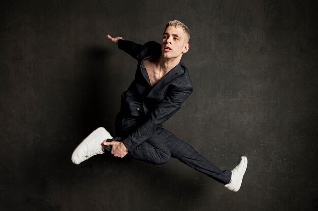 Side view of male performer in suit posing mid-air