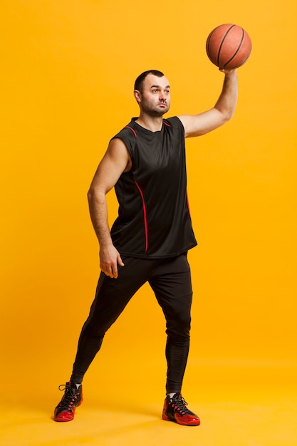 Free photo side view of male player holding basketball up