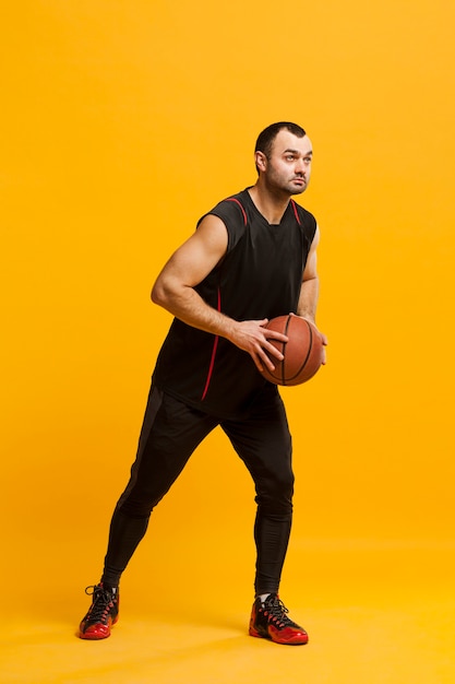 Side view of male player posing with basketball