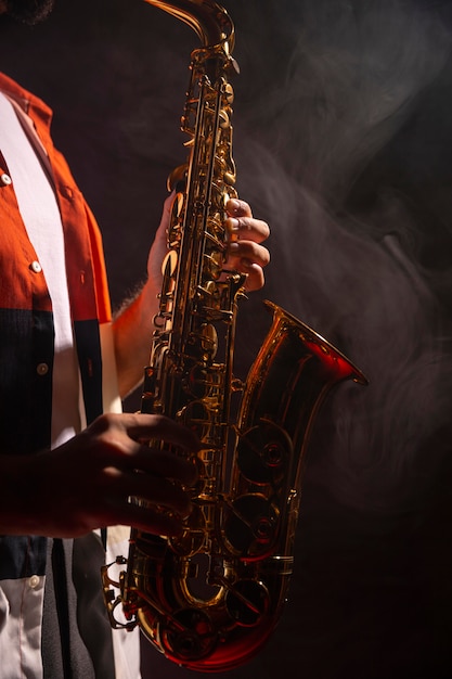 Side view of male playing the saxophone in the spotlight