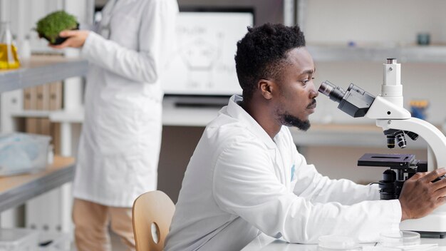 Вид сбоку мужчины-исследователь в лаборатории с микроскопом