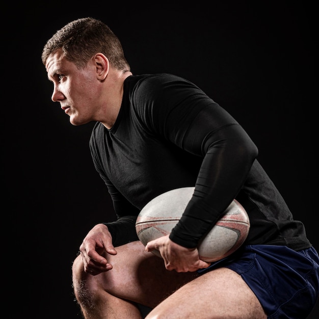 Foto gratuita vista laterale del giocatore di rugby maschio tenendo palla