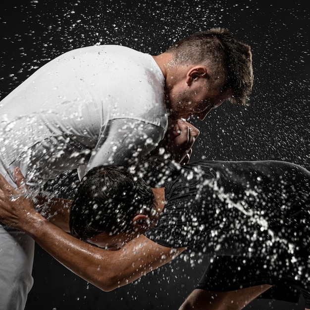 Side view of male rugby players with ball and water splashes