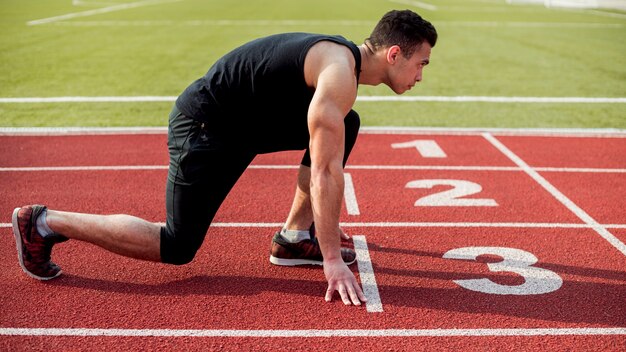 Side view of male runner sprinter getting ready to start the race