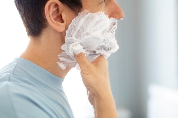 Side view man applying shaving cream