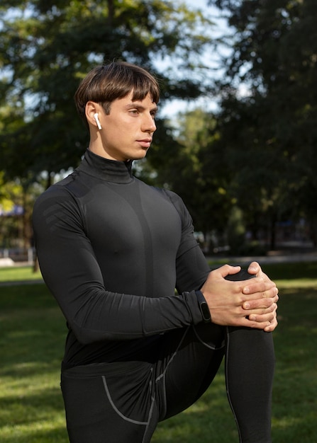 Side view of man in athletic wear and earbuds outdoors