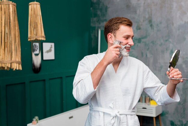 Side view of man in bathrobe shaving