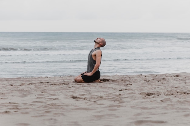 Side view of man on the beach meditating