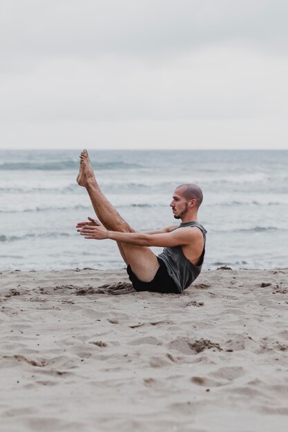 Side view of man on the beach in yoga position with copy space