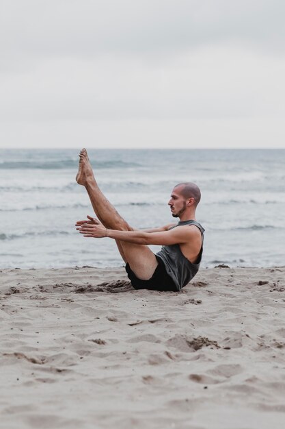 Вид сбоку человека на пляже в позе йоги с копией пространства
