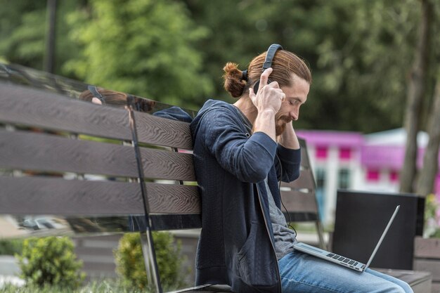 Side view of man on bench in the city with laptop