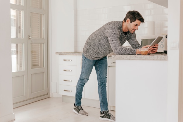 Side view man browsing tablet in kitchen