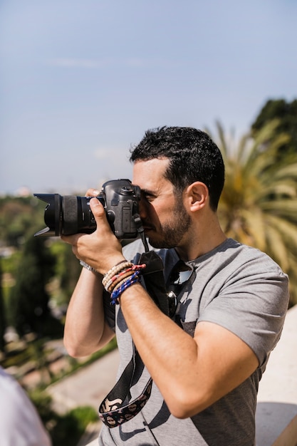 Side view of man capturing pica on camera