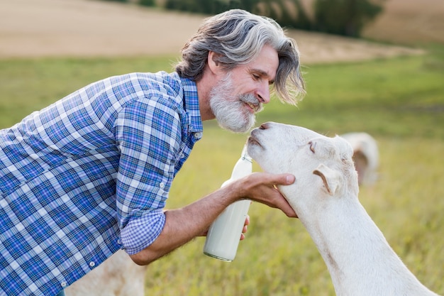 Free photo side view man carring goat