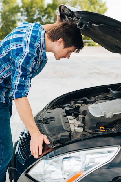 Side view of man checking car engine