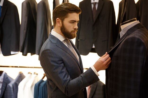 Side view of man choosing a jacket in shop