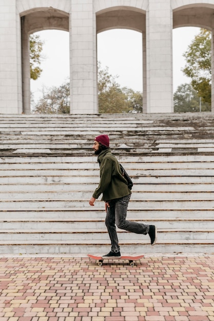 Side view of man in the city riding his skateboard