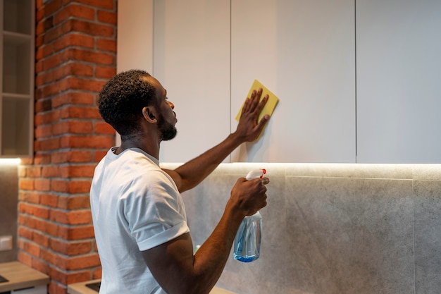 Side view man cleaning cabinet