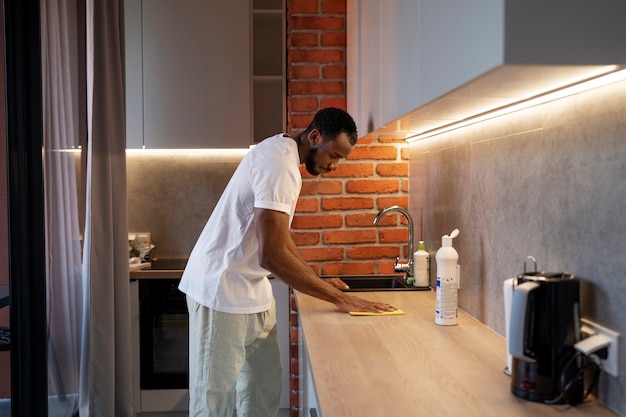 Side view man cleaning countertop