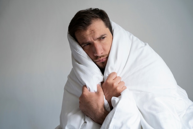 Free photo side view man covering himself with blanket