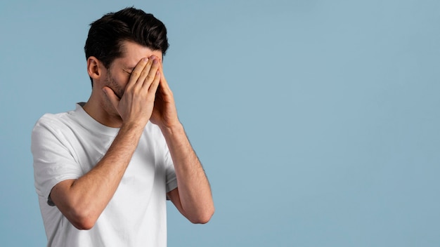 Side view of man covering his eyes with his hands