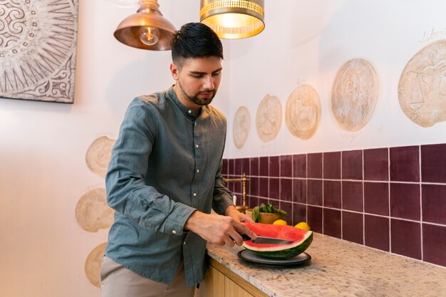 Side view man cutting watermelon