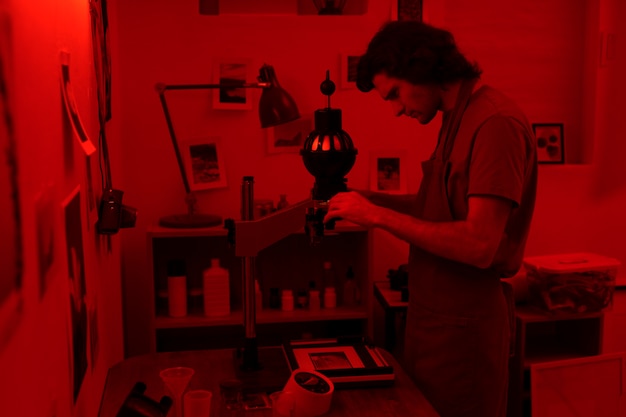 Side view man developing photos in darkroom