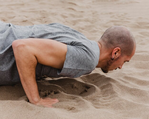 side view of man doing yoga on sand