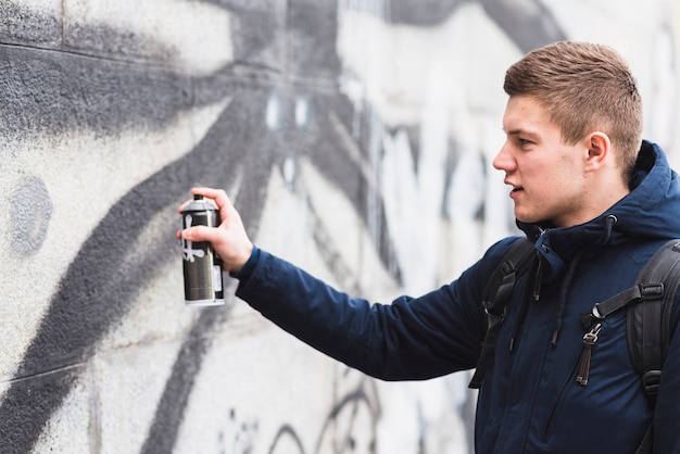 Free photo side view of a man drawing graffiti with spray