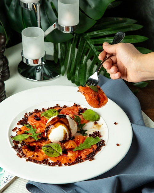 Side view man eating caprice salad with arugula and caviar