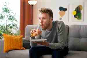 Free photo side view man eating croissant